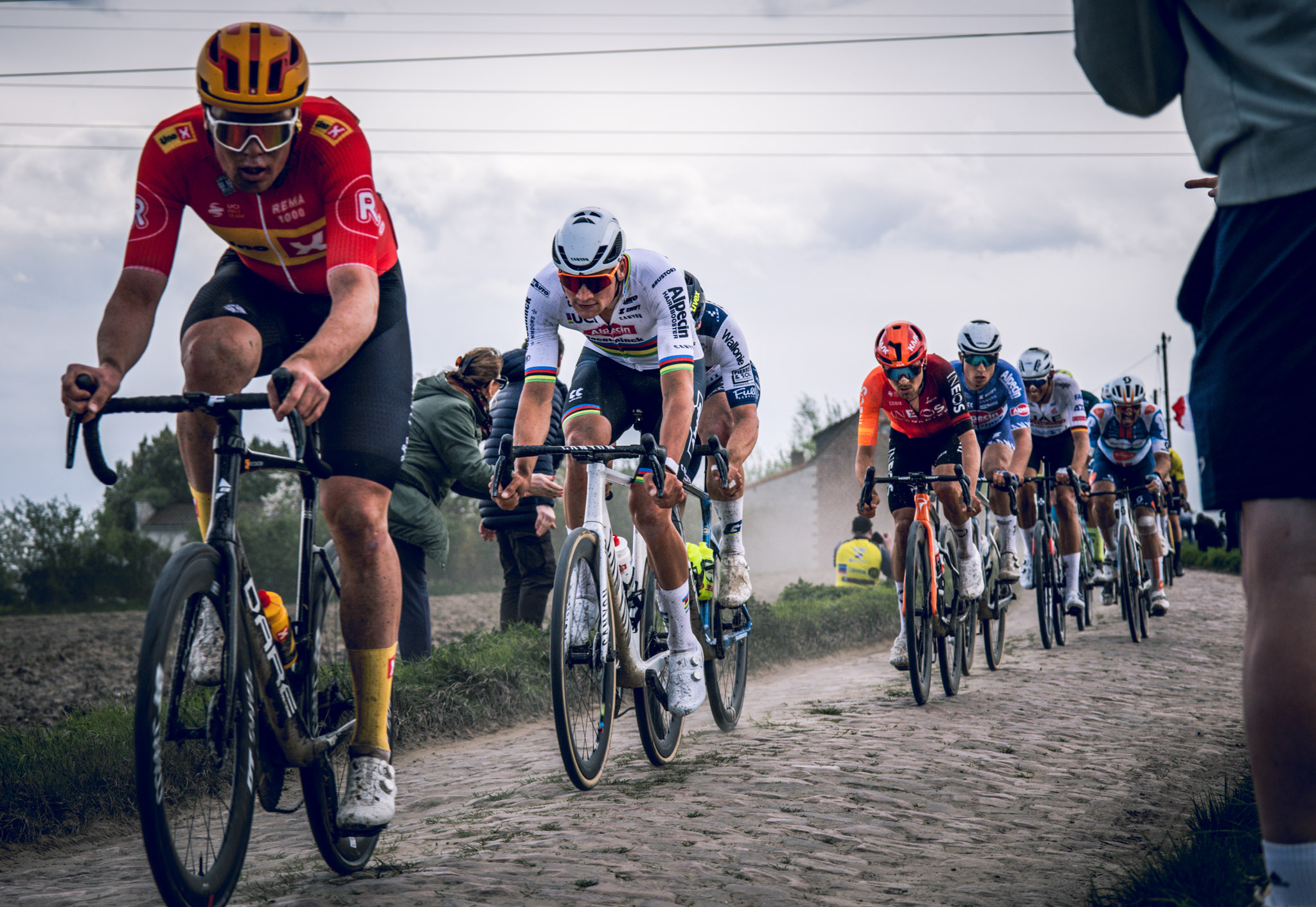 Professional peloton racing over rough cobbles during Paris-Roubaix.