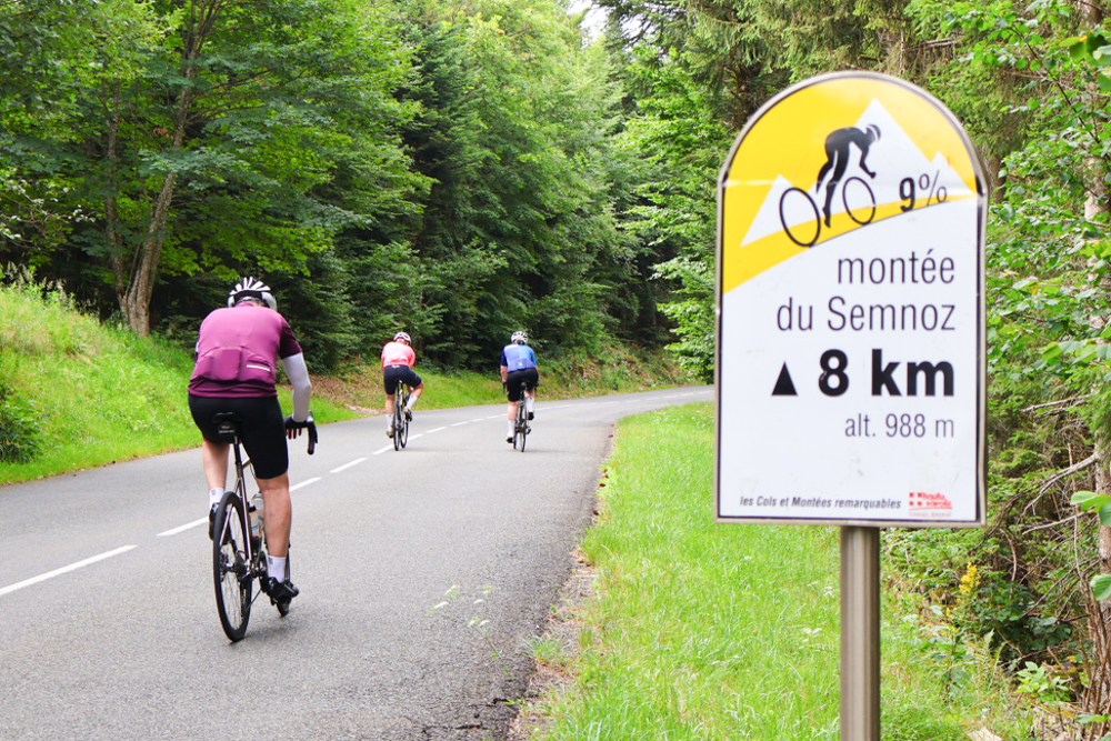 Cyclists climbing near the Semnoz ascent sign